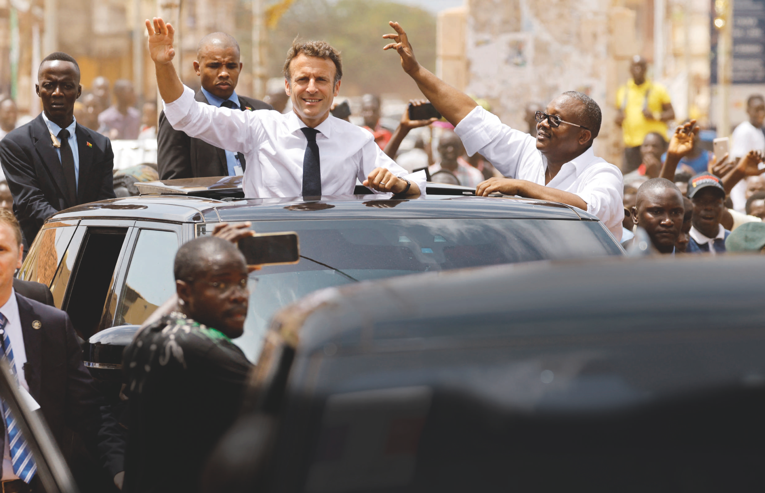 ​  Le président français Emmanuel Macron et son homologue de Guinée-Bissau Umaro Sissoco Embalo saluent la foule à Bissau, le 28 juillet 2022. LUDOVIC MARIN/AFP  ​