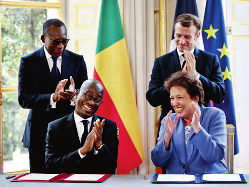 La signature de l'acte de transfert a eu lieu en France, à l’Élysée, le 9 novembre, en présence des deux chefs d'État (au second plan), du ministre béninois du Tourisme Jean-Michel Abimbola et de la ministre française de la Culture Roselyne Bachelot (au premier plan). POOL/AFP