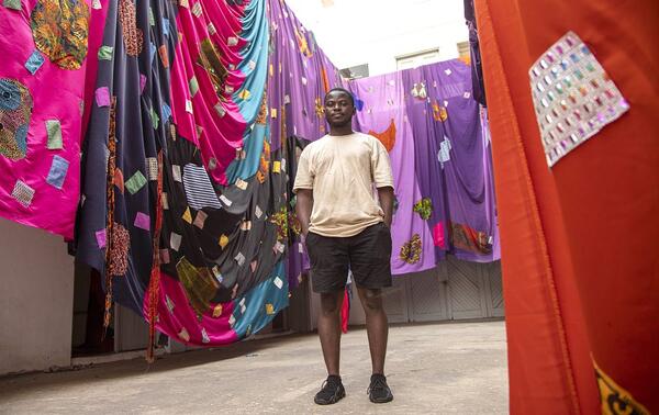 Emmanuel Aggrey Tieku entouré de ses créations faites d’étoffes. COURTESY DE L’ARTISTE ET ELLIPSE ART PROJECTS/PRIX ELLIPSE 2025